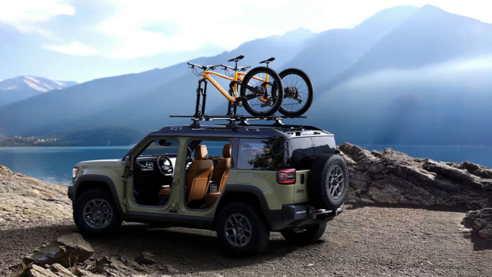 All-electric Jeep Recon SUV parked lakeside with bicycles mounted on the roof, illustrating Stellantis’ future access to Tesla Superchargers through NACS adoption.