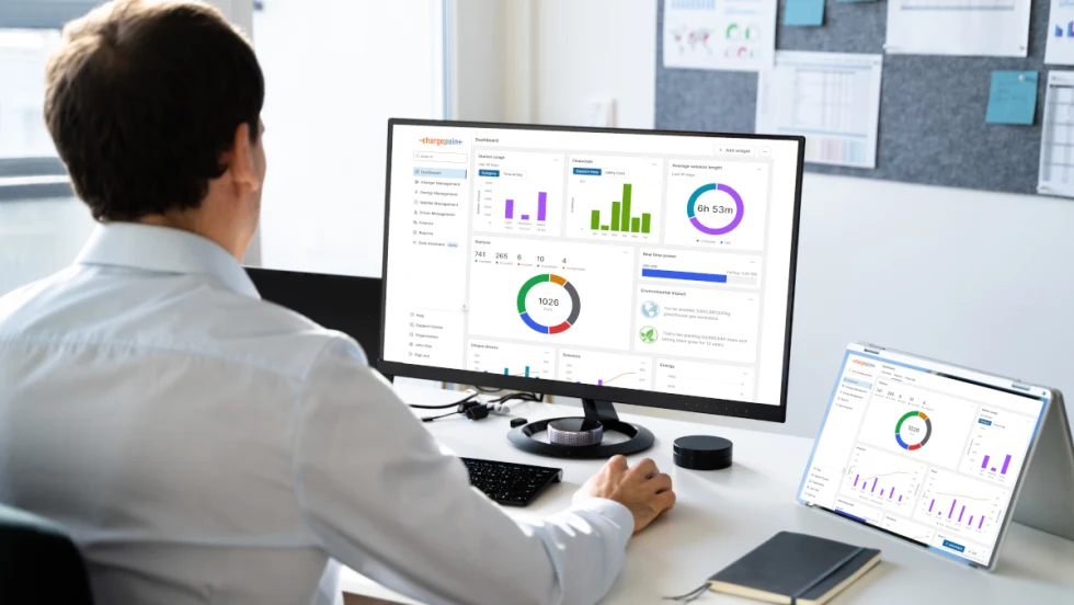 Man seated at desk and looking at charts and graphics on a computer and a tablet.