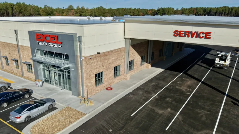 Slightly overhead view of a new truck dealership with one overhang labeled Service.