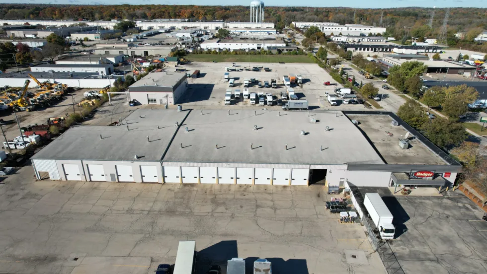 aerial view of an industrial looking large building with large parking areas.