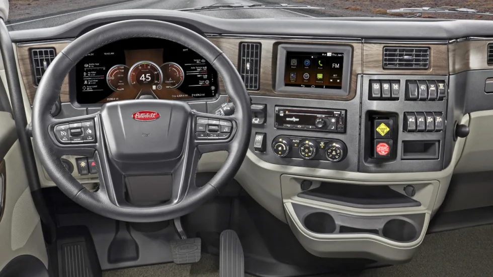 Inside view of a truck cab looking forward at the steering wheel and dash.