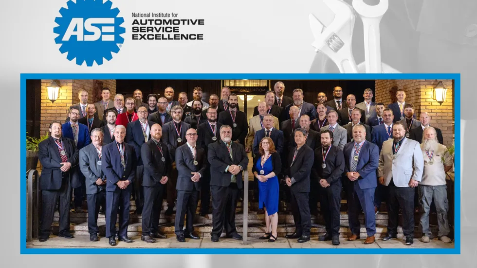 Group of award winners standing in three or four rows and all dressed in business attire. ASE logo top left.