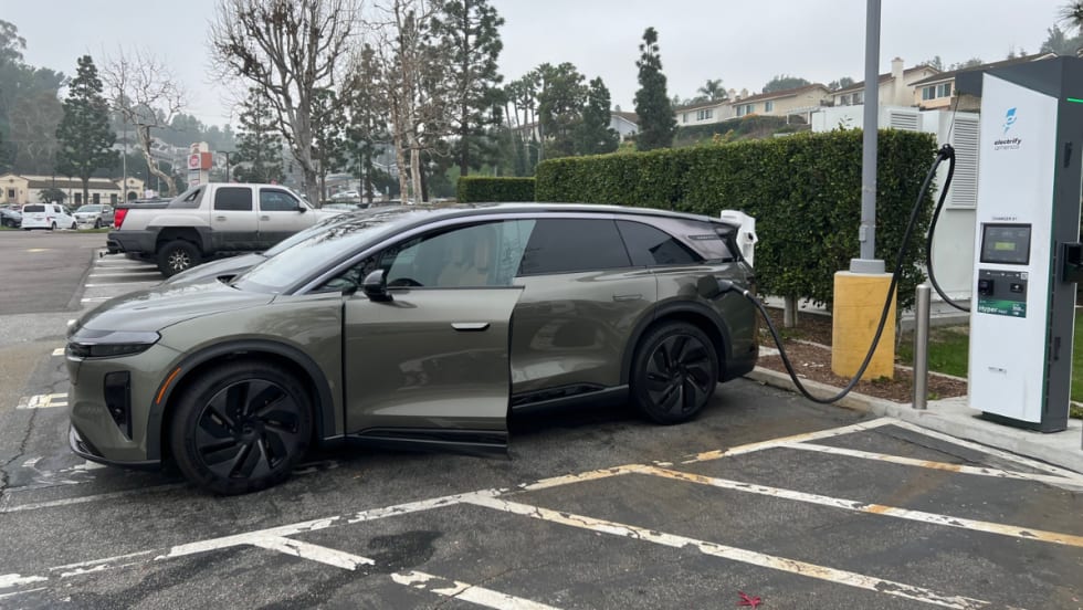 Lucid Gravity electric SUV plugged into a fast-charging station in a parking lot.