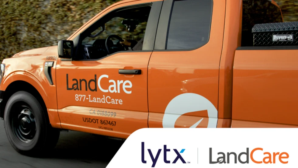 Side view closeup of an orange pickup truck with lettering for LandCare and at bottom right inset logos for Lytx and LandCare.