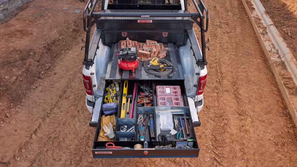 overhead photo of a truck bed tool storage drawer extended on a dirt job site.