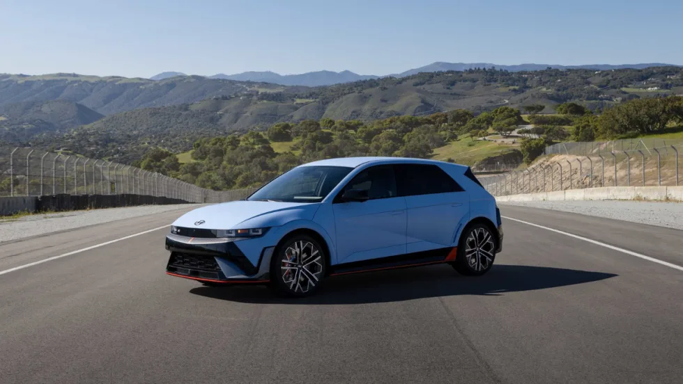 Blue 2026 Hyundai IONIQ 5 N performance electric hatchback parked on a racetrack with mountains in the background.