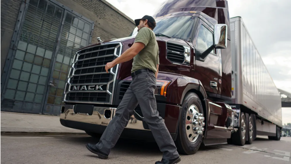 Man walks across in front of a Mack tractor trailer.