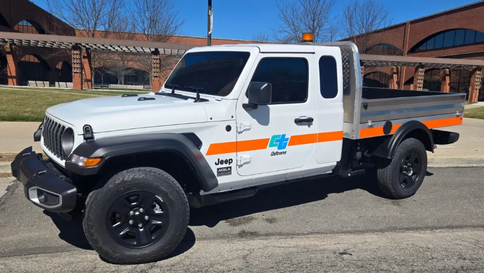 Acela Dispatcher 4x4 compact work truck with flatbed built on a modified Jeep Gladiator chassis, shown at NTEA Work Truck Week as a maneuverable, high-payload utility vehicle for fleets.