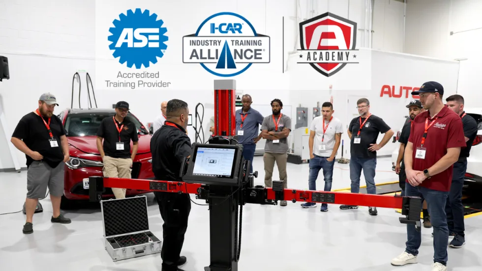 Group of automotive technicians in a circle learning during a training class, with three logos across the top of the image.