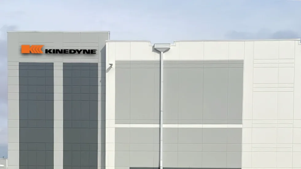 Artist's rendering of a white industrial building with Kinedyne logo.