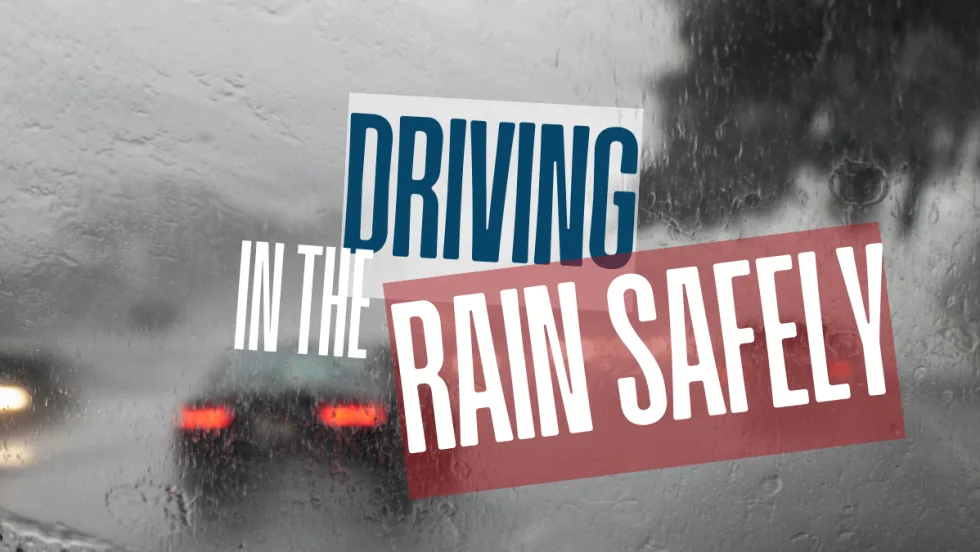 View through a rain-covered windshield with blurred brake lights ahead, illustrating reduced visibility and the need for cautious driving in wet conditions.