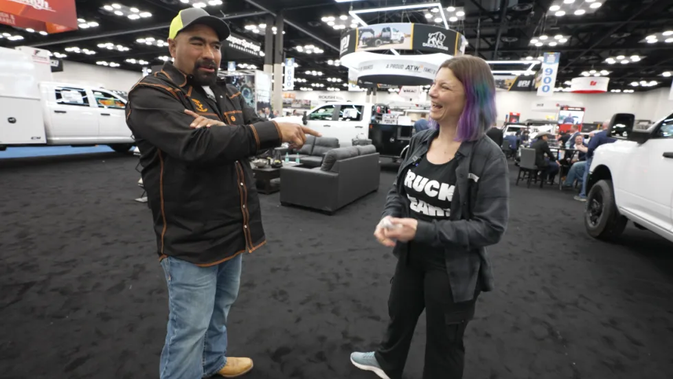 Juan Ibarra and Lauren Fletcher share a laugh during a Work Truck Week conversation surrounded by work trucks and exhibit booths