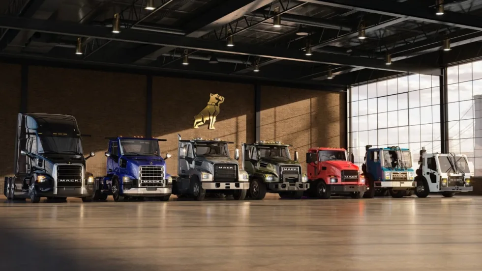 Lineup of Mack Trucks parked inside a warehouse.