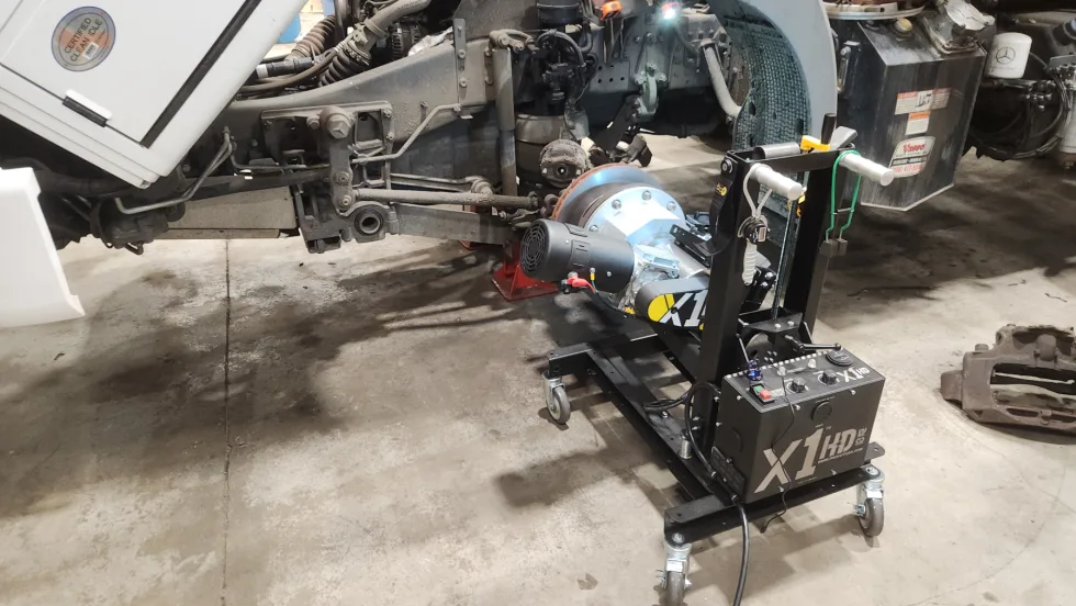 A brake lathe is attached to a truck wheel in a repair shop.