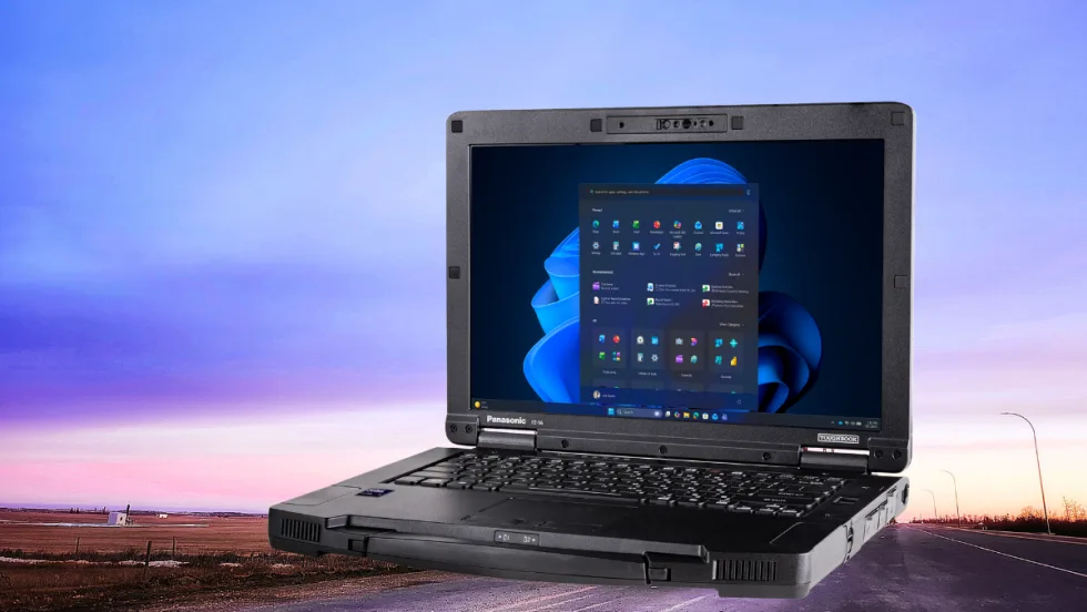 Photo of an open laptop computer against background of a sky at dusk.