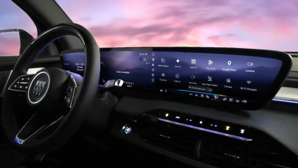 View of a GM vehicle dash with a large infotainment screen and purple sky viewed through windshield.