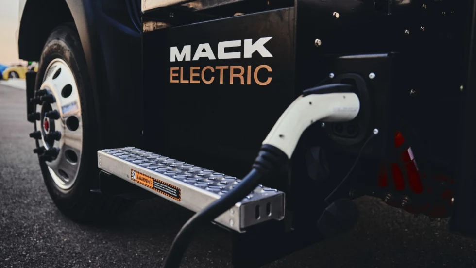 Closeup view of an EV charger plugged into a black truck with the logo for Mack Electric on the side.