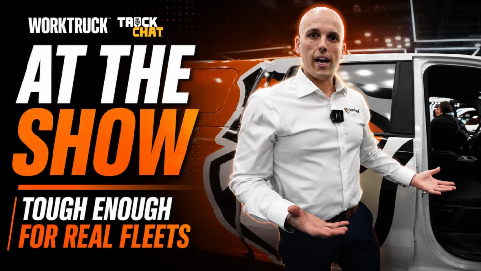 Work Truck Truck Chat thumbnail featuring a Sheldon Zitzmann standing beside a white work truck at a trade show. Large text reads “AT THE SHOW” and “TOUGH ENOUGH FOR REAL FLEETS” with Work Truck and Truck Chat branding in the upper left corner. The speaker gestures toward the truck interior while discussing fleet-focused floor liner solutions.