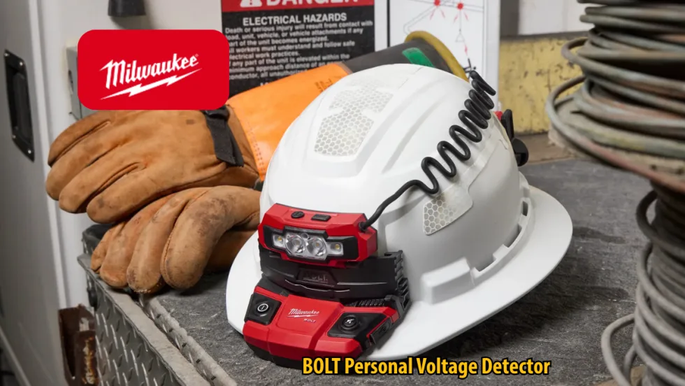 Milwaukee BOLT Personal Voltage Detector mounted on a white hard hat beside work gloves and electrical hazard signage. The safety device features integrated lights and a coiled cable in an industrial work environment.