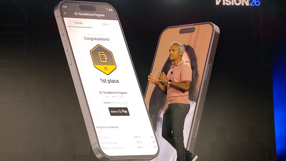 Presenter onstage at Motive Vision 26 conference beside a large smartphone display showing a driver rewards app, highlighting a first-place achievement in a Q1 Excellence Program with points, rankings, and Google Pay integration.