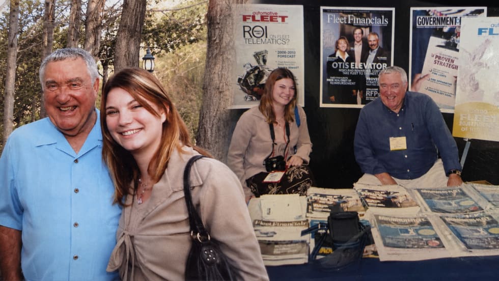 Composite image featuring two archival photos of Lauren Fletcher and Bobit Business Media founder Ed "Coach" Bobit. On the left, a younger Lauren stands smiling beside Coach outdoors. On the right, the two sit together at a Bobit Business Media trade show booth surrounded by early Automotive Fleet, Government Fleet, and Fleet Financials magazines.