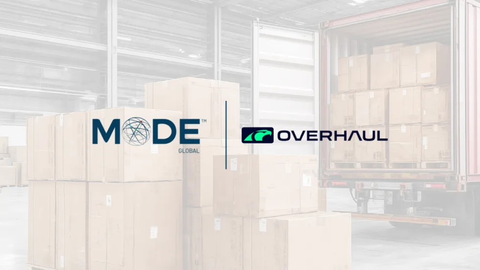 MODE Global and Overhaul logos displayed over a warehouse scene with stacked shipping boxes and a loaded trailer, illustrating a logistics technology partnership focused on freight visibility and supply chain operations.
