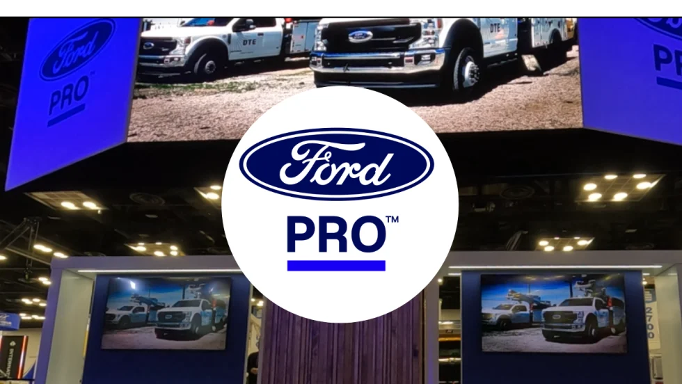 Ford Pro logo over a trade show booth displaying Ford commercial trucks on large digital screens, illustrating the company's commercial vehicle and fleet services showcased at an industry event.