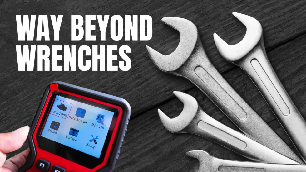 A handheld vehicle diagnostic scanner beside several wrenches on a dark wood surface, with the words “Way Beyond Wrenches” in large white text.