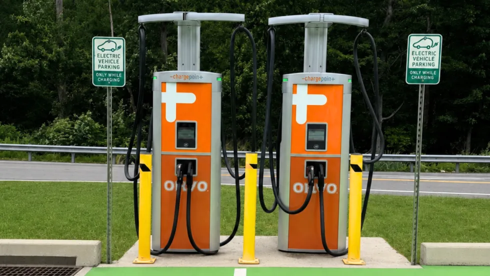 Two ChargePoint fast-charging stations branded ONVO stand in a roadside charging area, flanked by signs reserving parking for electric vehicles while charging.