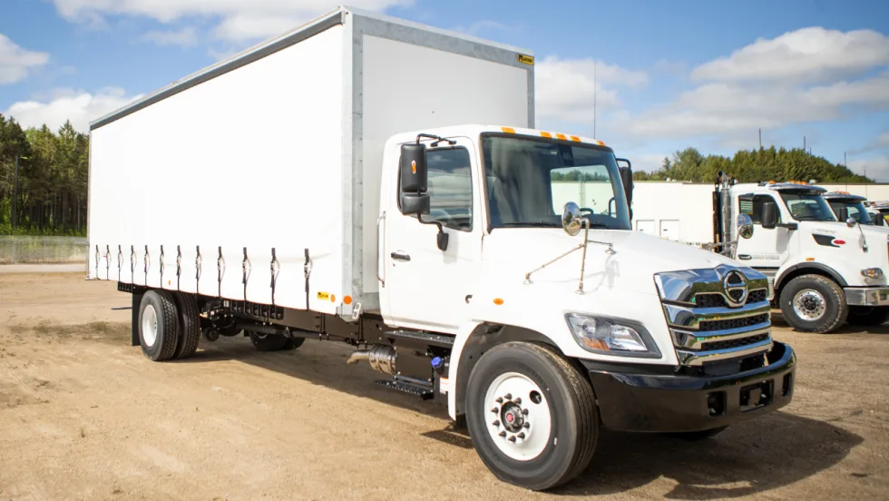 White medium-duty truck equipped with a Marion curtainside body featuring a retractable side curtain and multiple lower fasteners.