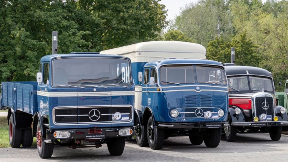 Three vintage Mercedes-Benz trucks, including blue and black models, displayed together outdoors as part of a classic truck collection. 