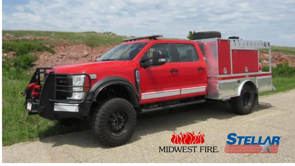 Red Midwest Fire service truck equipped with a Stellar body parked along a rural road, with Midwest Fire and Stellar logos displayed at the bottom.