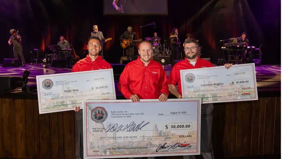 Three Ryder technicians in red shirts hold oversized prize checks after the 2026 Top Tech Championship, with a live band performing on stage behind them.