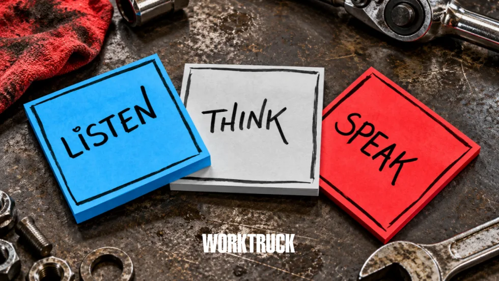 Three overlapping sticky notes in Work Truck brand colors reading “Listen,” “Think,” and “Speak” sit on a worn automotive workbench surrounded by tools and hardware.