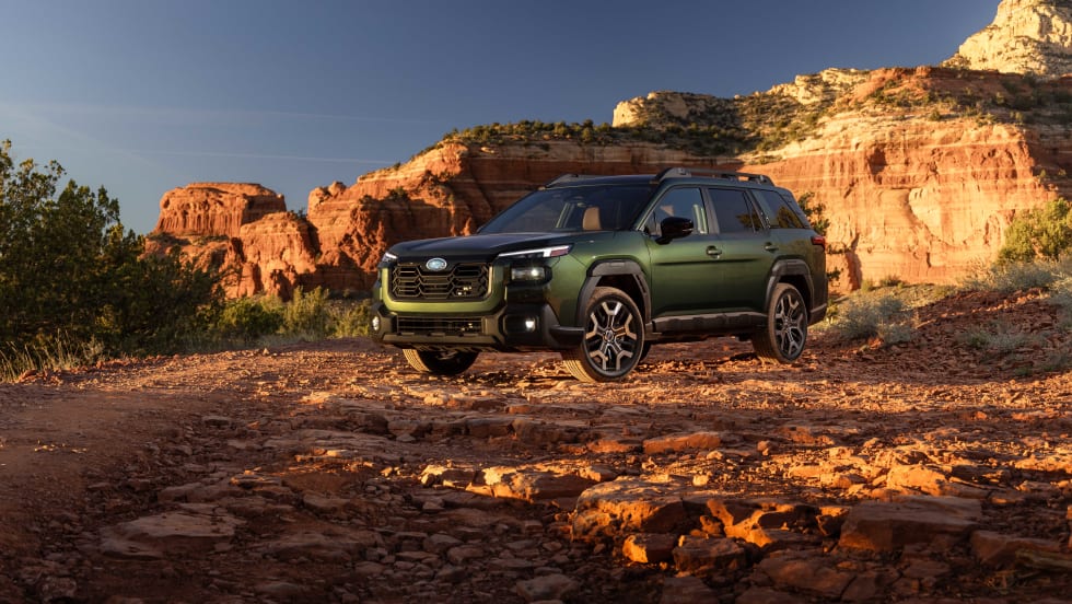 A green 2027 subaru outback drives in the mountains