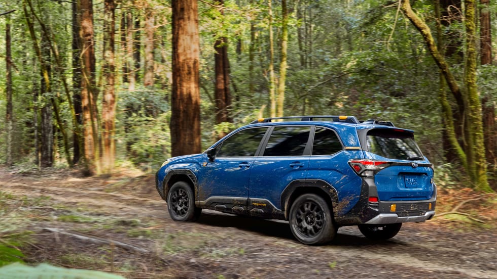 A 2026 BLue FOrester hybrid driving down a dirt road from the rear view