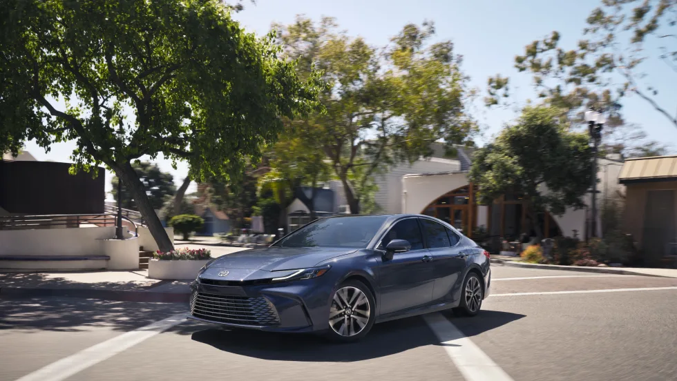 A blue Toyota Camry drives on a road