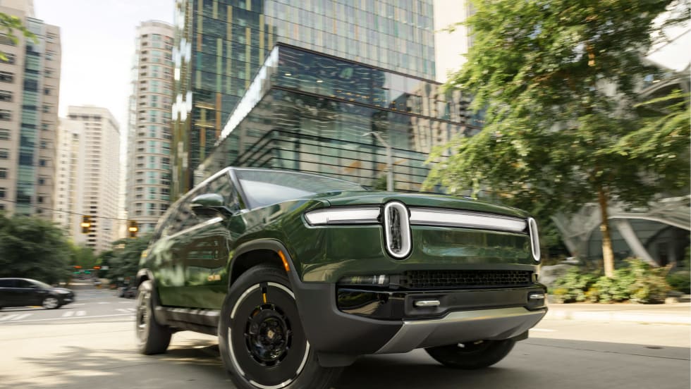 Rivian electric SUV driving through a city street, representing the company’s growing EV lineup and expansion plans.