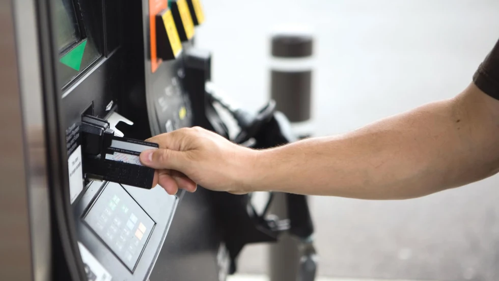Person inserting a payment card into a fuel pump card reader at a gas station