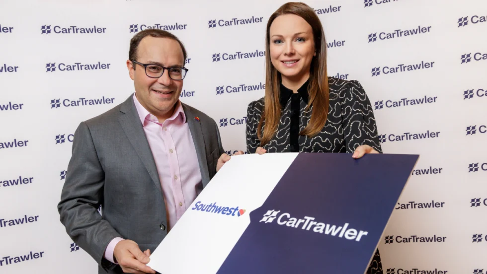 Two execs hold up a sign with Southwest and CarTrawler logos
