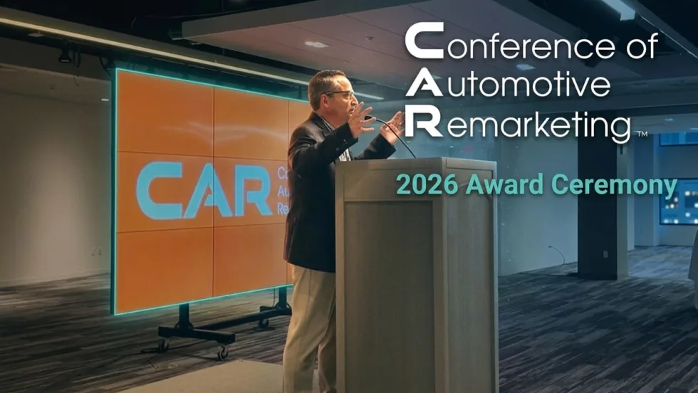 Chris Brown standing on stage at The Conference of Automotive Remarketing announcing this year's award winners. 