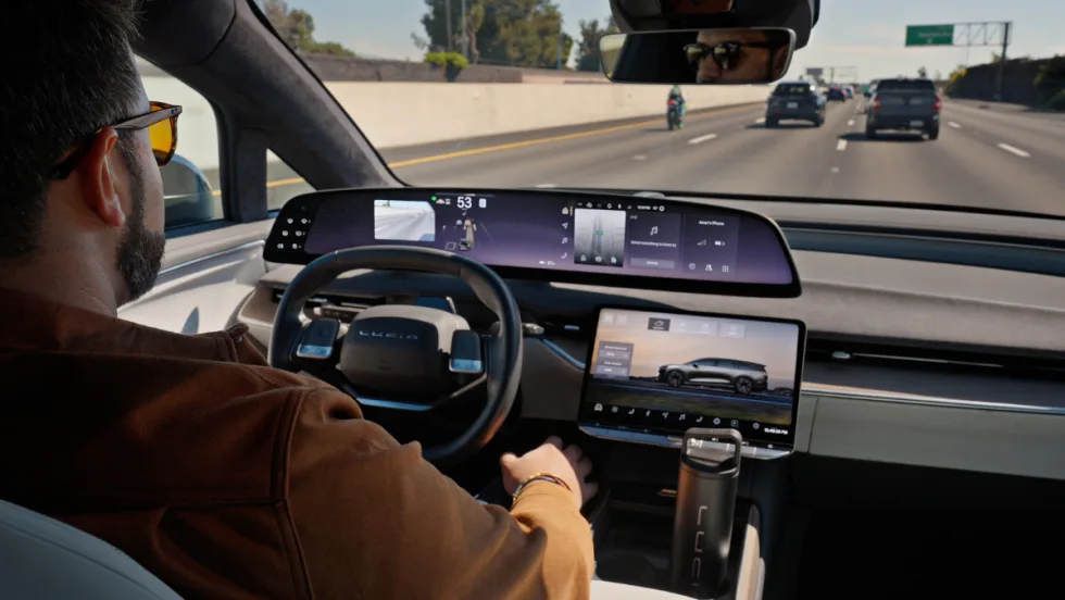 Man behind a steering wheel driving hands-free in a Lucid Gravity on the freeway.