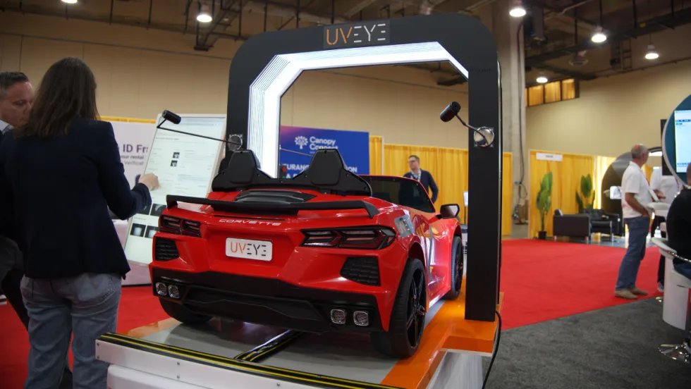 A red sports car sits underneath and AI-driven damage detection scanner.