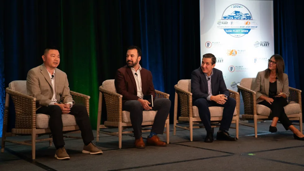 Four people sitting on stage doing presentation. 