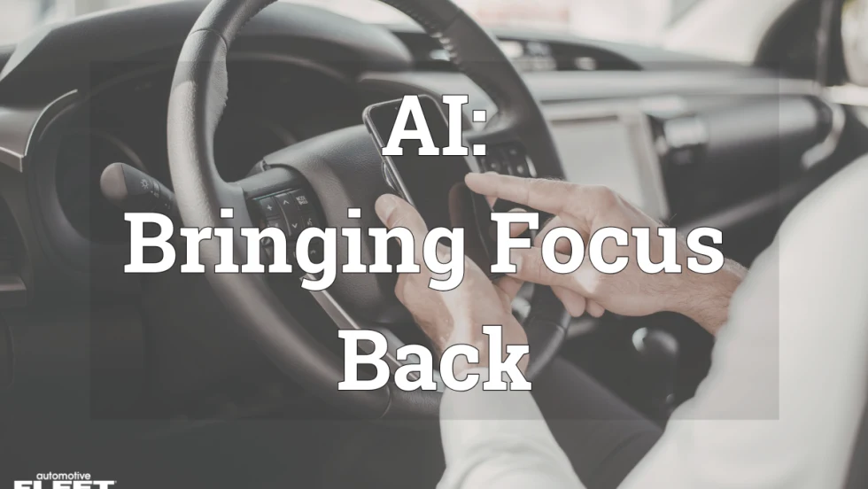 A person in a car on their phone behind the steering wheel.
