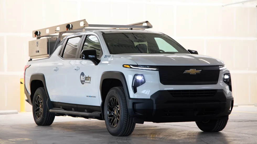 A full photo of a Silverado electric pickup rests in a stone garage with the McKinstry logo on its left side.
