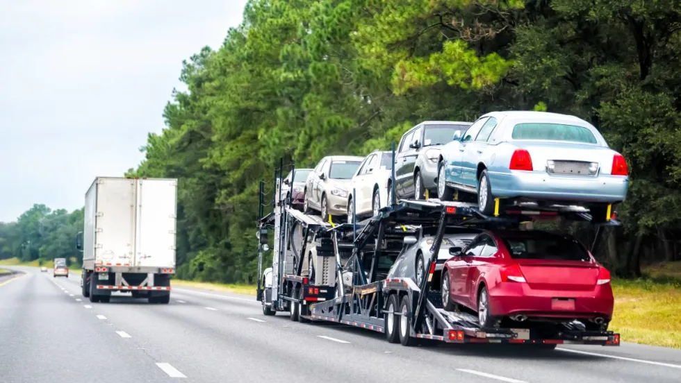 A double-decker stinger auto transporter driving down the freeway.