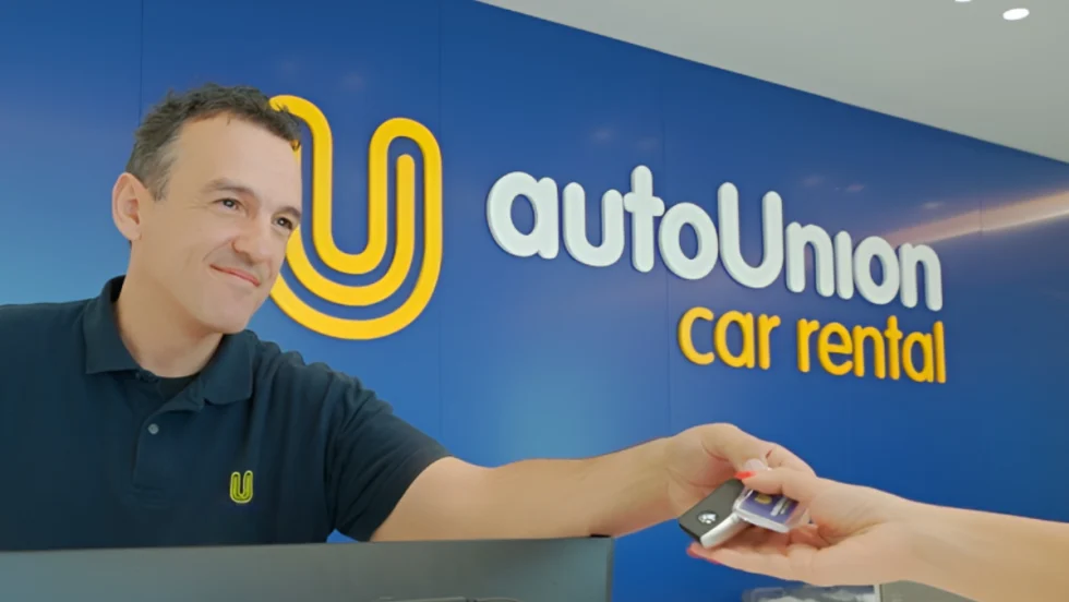 Rental car agent hands over key at AutoUnion Car Rental counter.
