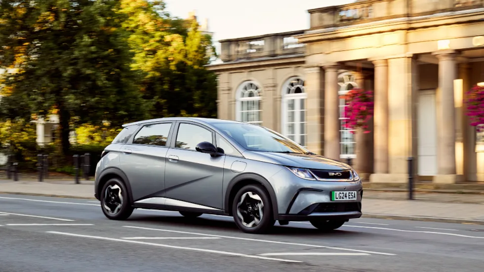 Photo of a gray BYD Dolphin sub-compact electric vehicle in front of a columned historic building.