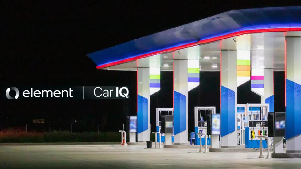 A gas station late at night sits on the right side of a dark photo.